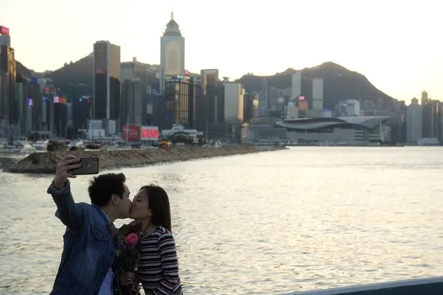 A couple kisses while taking a selfie by the Victoria Harbour during sunset on Valentine's Day, following the coronavirus disease (COVID-19) outbreak, in Hong Kong, China on February 14, 2022. (Photo by Lam Yik/Reuters)