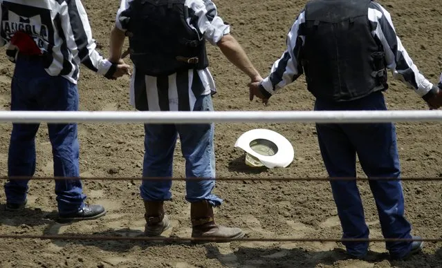 Prisoners hold hands and pray inside the ring before the start of the Angola Prison Rodeo in Angola, La., Saturday, April 26, 2014. Only the prison's most well-behaved inmates get to participate, according to the maximum-security prison's athletic director. (Photo by Gerald Herbert/AP Photo)