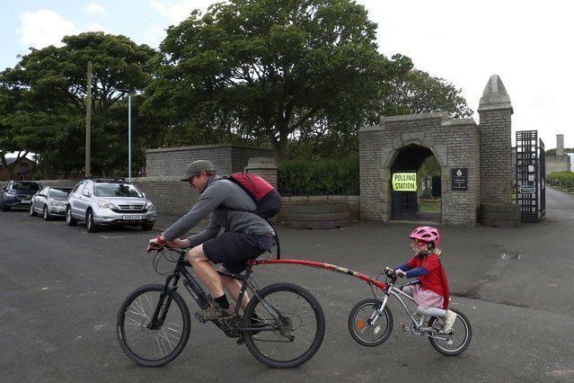 A man cycles with his daughter after casting his vote at Whitley Bay cemetery where there is polling station inside, in Whitley Bay, England, Thursday, July 4, 2024. Britain goes to the polls Thursday after Prime Minister Rishi Sunak called a general election. (Photo by Scott Heppell/AP Photo)