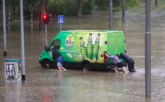 A group of men tries to push a van out of the flood water in Belgrade, Serbia, 15 May 2014. A state of emergency has been declared in Serbia due to severe floods caused by rain falling for more than 48 hours. (Photo by Koca Sulejmanovic/EPA)