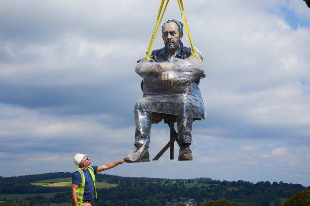 A three-metre-tall painted bronze sculpture, Seated Man 2016, by the artist Sean Henry, is lifted into its new home on July 23, 2019 at Yorkshire Sculpture Park in Wakefield, England. (Photo by Christopher Thomond/The Guardian)