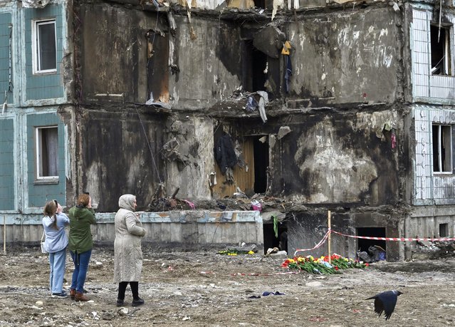 People pay their respects in front of a damaged multistory residential building, where a Russian strike killed 23 people, in Uman, Cherkasy region, on April 30, 2023. A Russian strike on a block of flats in the central Ukrainian city of Uman killed 23 people, including a baby boy on April 28, 2023. (Photo by Genya Savilov/AFP Photo)