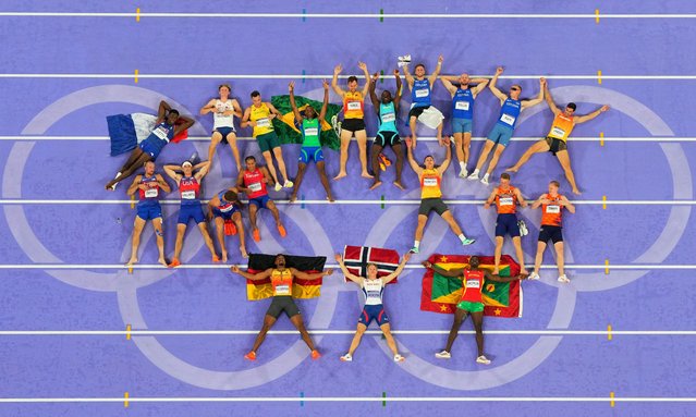 Men’s decathlon gold medallist Markus Rooth of Norway (bottom centre), silver medallist Leo Neugebauer of Germany (bottom left) and bronze medallist Lindon Victor of Grenada (bottom right) pose with their national flags and the rest of the decathlon competitors at Stade de France in Saint-Denis, France on August 03, 2024. (Photo by Fabrizio Bensch/Reuters)