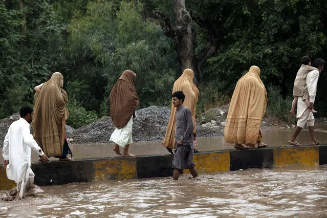 People flee the flooded areas in Charsadda district of Khyber Pakhtunkhwa province, Pakistan, 23 July 2015. A week of heavy monsoon rains caused flooding in Chitral district of the north-western province of Khyber-Pakhtunkhwa, cutting the region off, said Ahmed Kamal, spokesman for the national disaster agency. At least 200,000 people were stranded, Kamal said in the capital Islamabad, adding that continued rain were hampering the rescuers. (Photo by Arshad Arbab/EPA)