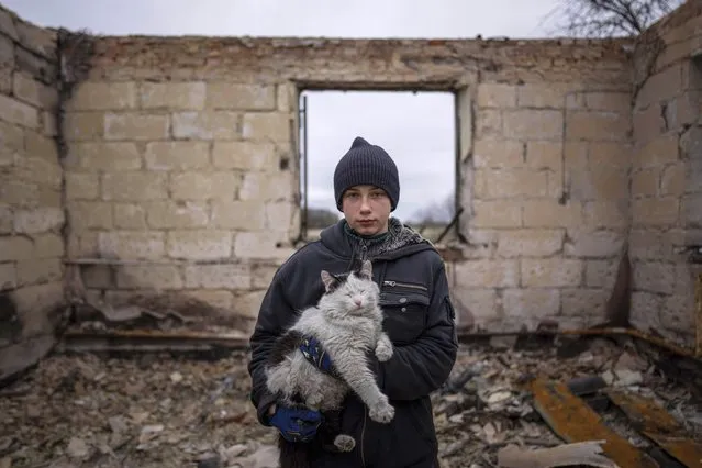 Danyk Rak, 12, holds a cat standing on the debris of his house destroyed by Russian forces' shelling in the outskirts of Chernihiv, Ukraine, Wednesday, April 13, 2022. After shelling Danyk's mother Liudmila Koval had to have her leg amputated and was injured in her abdomen. She is still waiting for proper medical treatmen. (Photo by Evgeniy Maloletka/AP Photo)