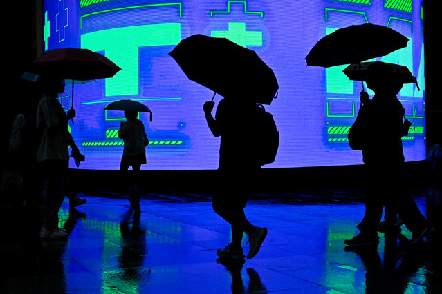 People holding umbrellas walk during a rainstorm in Beijing on July 30, 2024. (Photo by Pedro Pardo/AFP Photo)