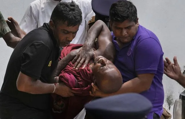 An injured Sri Lankan Buddhist monk is being carried away who among many other anti-government protesters were injured after attacked by government supporters outside prime minister Mahinda Rajapaksa's residence in Colombo, Sri Lanka, Monday, May 9, 2022. (Photo by Eranga Jayawardena/AP Photo)