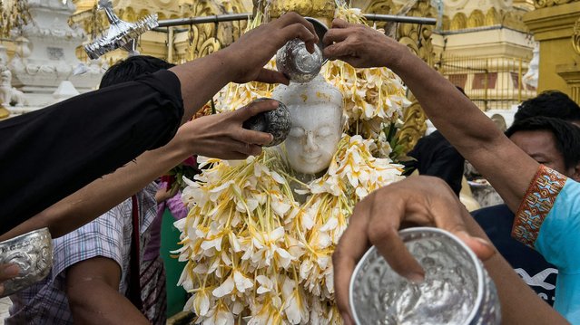 Devotees pour water on a Buddha statue as they visit Shwedagon Pagoda during the full moon day of Waso, a sacred day in the Myanmar lunar calendar that marks the beginning of Buddhist Lent, in Yangon on July 20, 2024. (Photo by Sai Aung Main/AFP Photo)