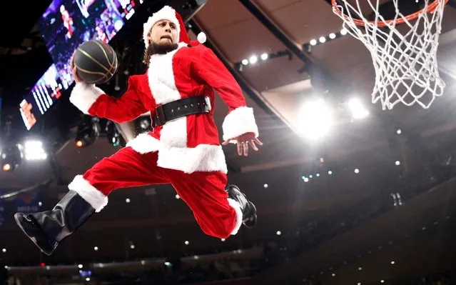 A “dunking Santa” gets airborne for a shot after using a trampoline to get the height during a timeout during the second half of an NBA basketball game between the New York Knicks and the Washington Wizards in New York, Monday, December 23, 2019. The Wizards won 121-115. (Photo by Kathy Willens/AP Photo)