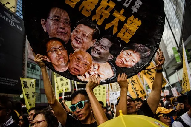 A protester holds a wok-shaped artwork with pictures showing the faces of (top row L-R) Chairman of the Standing Committee of the National People's Congress of China Zhang Dejiang, Chinese President Xi Jinping, former chief executive of Hong Kong Leung Chun-ying, new Chief Executive of Hong Kong Carrie Lam, (bottom row L-R) Director of the Liaison Office of the Central People's Government in Hong Kong Zhang Xiaoming, former Hong Kong chief executive Tung Chee-hwa and Director of the Hong Kong and Macau Affairs Office Wang Guangya during a protest march in Hong Kong on July 1, 2017, coinciding with the 20th anniversary of the city's handover from British to Chinese rule. China's President Xi Jinping warned July 1 that any challenge to Beijing's control over Hong Kong crossed a “red line”, as thousands calling for more democracy marched through the city 20 years since it was handed back by Britain. (Photo by Anthony Wallace/AFP Photo)