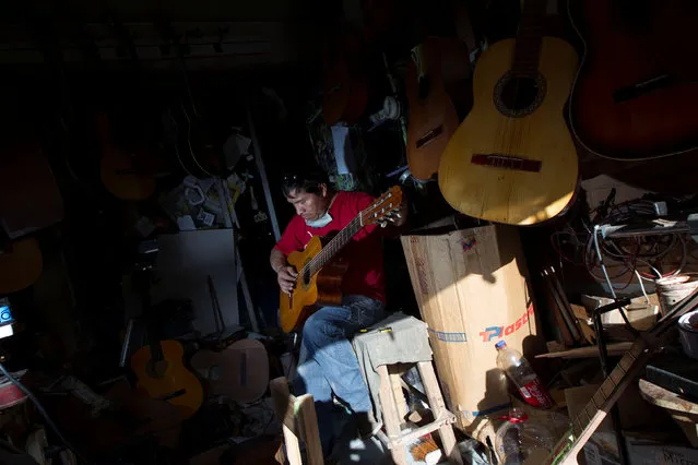 Ecuadorian luthier Ivan Ibujes plays a guitar after repairing it at his shop in Quito, June 17, 2016. (Photo by Guillermo Granja/Reuters)