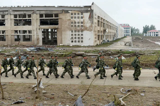 Chinese paramilitary policemen walk past damaged factory buildings in Funing county in Yancheng city in eastern China's Jiangsu Province Friday, June 24, 2016. (Photo by Chinatopix via AP Photo)