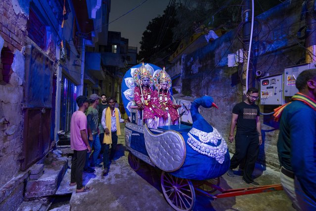 Indian artists dressed as Hindu deities Rama, left, and Lakshman, right, sit on a chariot being pulled by laborer that passes through the narrow alleys ahead of a religious procession during the Dussehra festival also known as Vijayadashami, the day Rama killed demon king Ravana who had abducted Rama's wife Sita, celebrating the victory of good over evil on 12th october in Prayagraj in the northern Indian state of Uttar Pradesh, India, Wednesday, October 9, 2024. (Photo by Rajesh Kumar Singh/AP Photo)