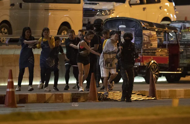 People who were able to get out of Terminal 21 Korat mall, are escorted outside by armed commando soldiers in Nakhon Ratchasima, Thailand on Sunday, February 9, 2020. (Photo by Sakchai Lalitkanjanakul/AP Photo)