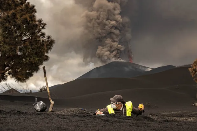 A scientist from IGME-CSIC (Spanish National Research Council) collects samples of volcanic ashes on the Canary island of La Palma, Spain, Thursday, November 18, 2021. Scientists from around the world flocking to an eastern Atlantic Ocean island are using an array of new technologies available to them in 2021 to scrutinize – from land, sea, air, and even space – a rare volcanic eruption. (Photo by Taner Orribo/AP Photo)