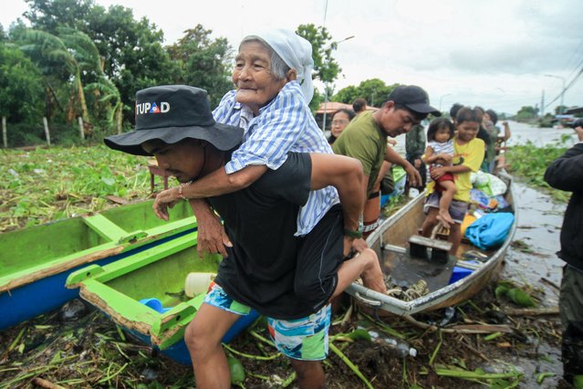 An elderly woman is carried by a volunteer rescuer as residents are evacuated to safer grounds in Bato town, Camarines Sur province South of Manila on October 23, 2024. Torrential rains driven by the storm have turned streets into rivers, submerged entire villages and buried some vehicles up to their door handles in volcanic sediment knocked loose by the downpour. (Photo by Charism Sayat/AFP Photo)