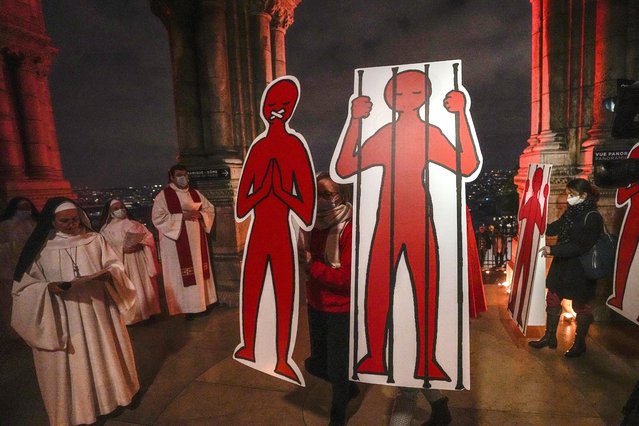 Members of Aide a l'Eglise en Detresse (aid to the church in distress) hold signs with silhouettes during a procession with catholic clergy in support of the persecuted Christians around the world at Sacre-Coeur Basilica in Paris, Wednesday, November 24, 2021. (Photo by Michel Euler/AP Photo)