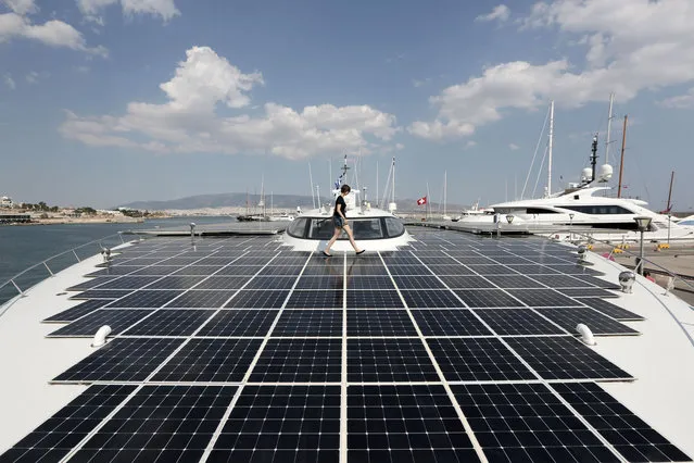 PlanetSolar press officer Julia Tames walks across the deck of the MS Turanor PlanetSolar, the world's largest solar-powered boat, moored at Zea Harbor, in Athens, on Tuesday August 5, 2014. The 35-meter (115-foot) vessel is in Greece to take part in a Swiss-Greek underwater archaeology project to survey the seabed off a major prehistoric site, in hope of finding traces of what could be one of the earliest villages in Europe. (Photo by Thanassis Stavrakis/AP Photo)
