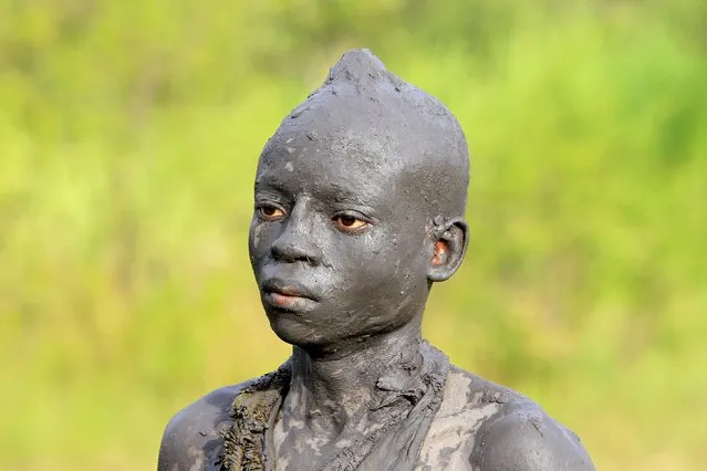 A Bukusu boy stands smeared with mud in preparation for the circumcision ritual currently ongoing in Kenya's western region of Bungoma August 9, 2014. The Bukusu tribe from Western Kenya has stuck to their long standing and strong tradition in the rites of passage to adulthood, through the circumcision ritual where young boys face the circumciser's knife without flinching. (Photo by Noor Khamis/Reuters)