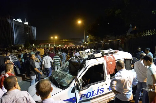 A crowd passes a wrecked police vehicle near military headquarters in Ankara, Turkey July 16, 2016. (Photo by Reuters/Stringer)