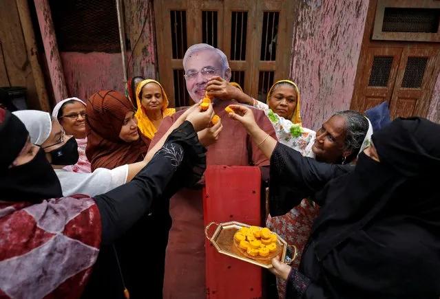Muslim women offer sweets to a cardboard cut-out of Indian Prime Minister Narendra Modi to celebrate on the eve of the Hindu festival of Raksha Bandhan, during which a sister ties one or more of “rakhi” or the sacred threads, onto her brother's wrist to ask him for her protection, in Ahmedabad, India on August 10, 2022. (Photo by Amit Dave/Reuters)