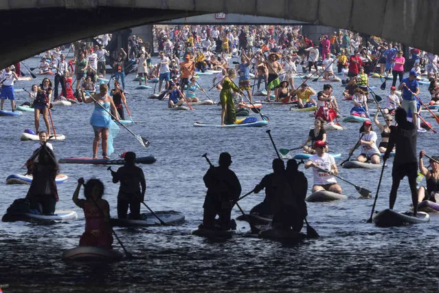 People steer their stand-up paddle (SUP) boards along Fontanka River during annual costumed “Fontanka” SUP-boards festival in St. Petersburg, Russia, Saturday, August 6, 2022. (Photo by Dmitri Lovetsky/AP Photo)