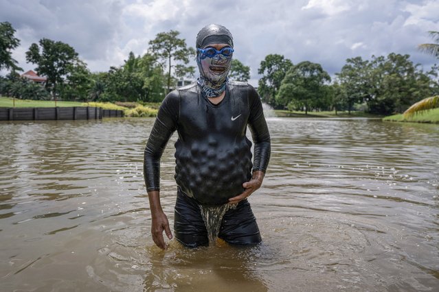 This picture taken on November 11, 2024 shows Sumadi Ibrahim, 51, walking with golf balls he recovered inside his diving suit in a pond at a course in Shah Alam, on the outskirts of Kuala Lumpur. After two decades plunging Malaysian seas to defend his country, navy frogman Sumadi Ibrahim has retired to the golf course – diving water hazards to retrieve mis-hit balls to make a living. For 22 years Sumadi served in the Royal Malaysian Navy, deployed aboard ships patrolling the shark-riddled waters off the Pacific archipelago. (Photo by Mohd Rasfan/AFP Photo)