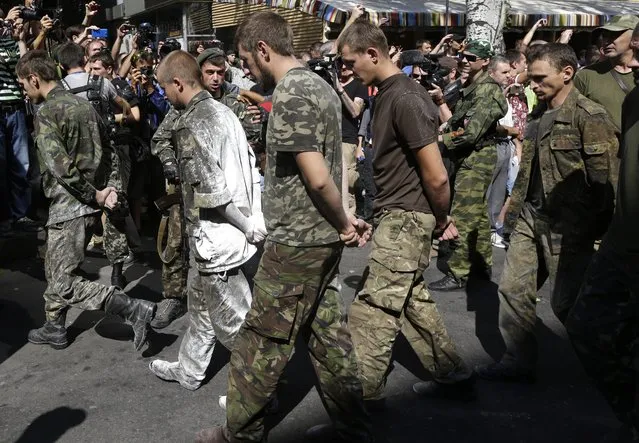 Pro-Russian rebels escort prisoners of war from the Ukrainian army in a central square in Donetsk, eastern Ukraine, Sunday, August 24, 2014. Ukraine has retaken control of much of its eastern territory bordering Russia in the last few weeks, but fierce fighting for the rebel-held cities of Donetsk and Luhansk persists. (Photo by Sergei Grits/AP Photo)