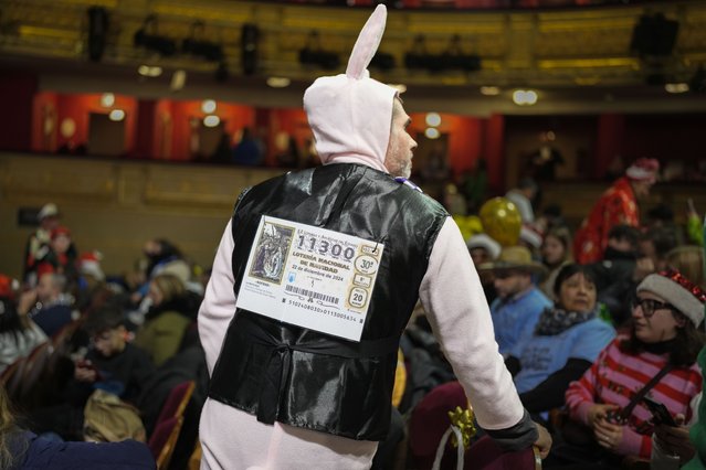 A spectator waits for the start of the annual Christmas lottery draw, known as El Gordo, or The Fat One, at Madrid's Teatro Real, Spain, on Sunday, December 22, 2024. (Photo by Bernat Armangue/AP Photo)