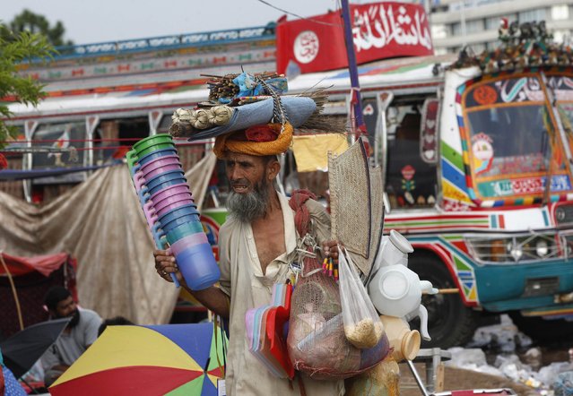 A man peddles household goods to supporters (unseen) of populist cleric Tahir ul-Qadri, leader of political party Pakistan Awami Tehreek (PAT), in front of the Parliament house building during the Revolution March in Islamabad August 27, 2014. Thousands of protesters, led by opposition leader Imran Khan and Qadri, are now camped out in the heart of Islamabad - the so-called “Red Zone”. (Photo by Akhtar Soomro/Reuters)