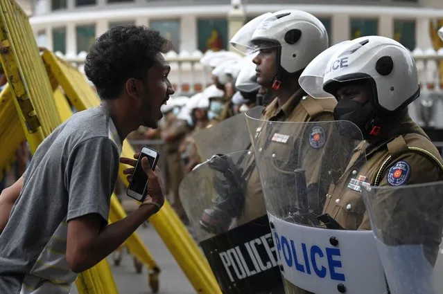 A demonstrators interacts with Police special task force personnel (R) standing guard while blocking a road as demonstrators take part in a protest march against Sri Lankan President Ranil Wickremesinghe towards the Presidential secretariat office in Colombo on July 22, 2022. Sri Lankan security forces demolished the main anti-government protest camp in the capital, evicting activists in a pre-dawn assault on July 22 that raised international concern for dissent under the new pro-West president. (Photo by Arun Sankar/AFP Photo)