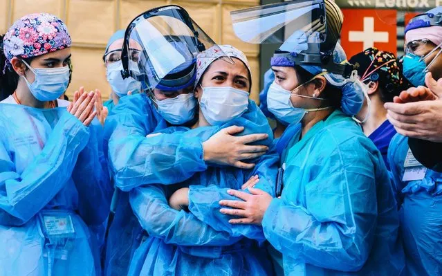 Medical workers are seen outside Lenox Health Greenwich Village in New York on April 28, 2020, as people applaud at 7pm to show their gratitude to medical staff and essential workers on the front lines of the coronavirus pandemic. (Photo by Nina Westervelt/Rex Features/Shutterstock)