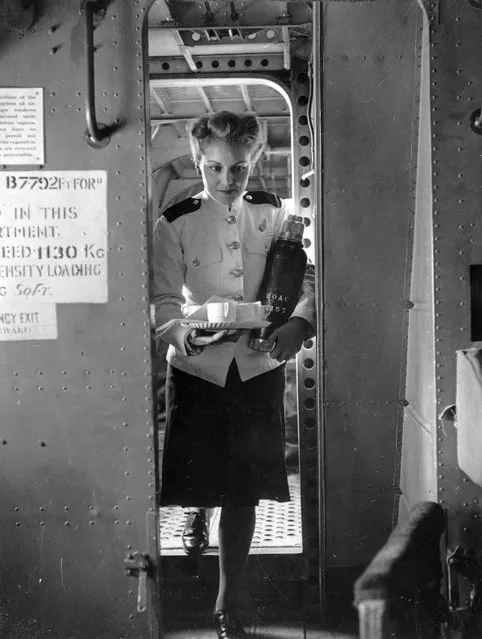 British and Overseas Airways air stewardess Peggy Keyte brings a tray of coffees to the passengers in her aircraft, during a World War II flight, circa 1945. (Photo by Fred Ramage/Keystone/Getty Images)