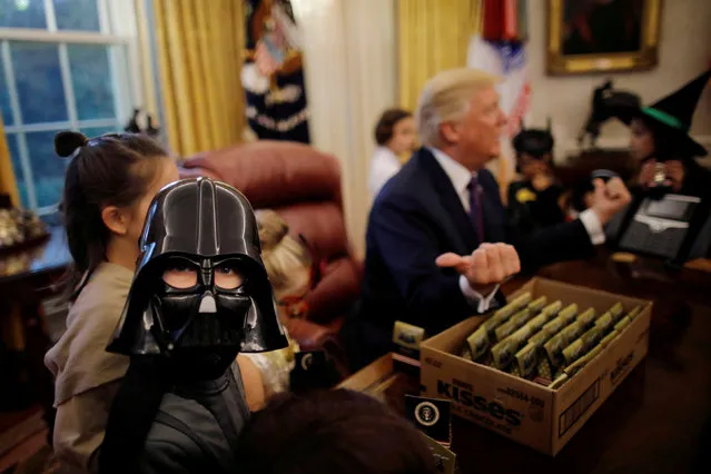 U.S. President Donald Trump gives out Halloween treats to children of members of press and White House staff in the Oval Office of the White House in Washington, DC, U.S. October 27, 2017. (Photo by Carlos Barria/Reuters)