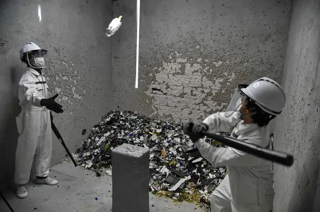 This photograph taken on October 19, 2017 shows Fragment Room employees smashing bottles during a demonstration in a “rage room” in Singapore. Bad day at the office? In high- pressured Singapore there is now a solution – a “rage room” that lets stressed- out people take a baseball bat to items ranging from glass bottles to televisions. (Photo by Roslan Rahman/AFP Photo)
