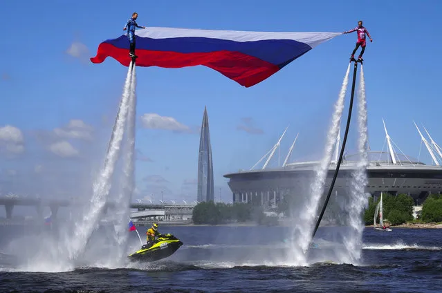 Members of the Russian hydroflight team hold the Russian national flag during the Day of Russia celebration in St.Petersburg, Russia, Friday, June 12, 2020, with business tower Lakhta Centre, the headquarters of Russian gas monopoly Gazprom and Gazprom Arena soccer stadium in the background. (Photo by Dmitri Lovetsky/AP Photo)