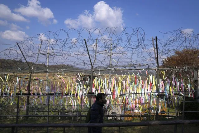 A visitor walks near the wire fences decorated with ribbons with messages wishing for the reunification of the two Koreas at the Imjingak Pavilion in Paju, South Korea, Friday, October 28, 2022. North Korea fired two short-range ballistic missiles toward the sea on Friday in its first ballistic weapons launches in two weeks, as the U.S. military warned the North that the use of nuclear weapons “will result in the end of that regime”. (Photo by Lee Jin-man/AP Photo)