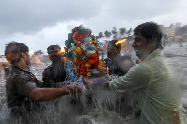 Devotees carry an idol of the Hindu god Ganesh, the deity of prosperity, into the Arabian Sea on the fifth day of the ten-day-long Ganesh Chaturthi festival in Mumbai, India, September 21, 2015. (Photo by Danish Siddiqui/Reuters)