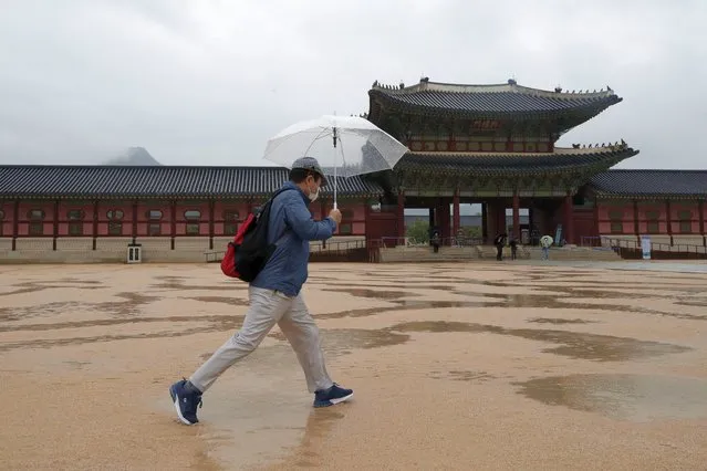 A man wearing a face mask to help protect against the spread of the new coronavirus walks at the Gyeongbok Palace, one of South Korea's well-known landmarks, in Seoul, South Korea, Wednesday, July 22, 2020. Just days after South Korean officials hopefully declared the country’s COVID-19 epidemic was coming under control, health authorities reported dozens of new cases following a dual rise in local transmissions and imported infections. (Photo by Lee Jin-man/AP Photo)