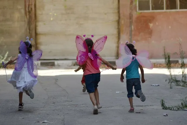 Palestinian girls wearing costumes play in the besieged Yarmuk refugee camp in the Syrian capital Damascus on August 31, 2015. (Photo by Rami Al-Sayed/AFP Photo)