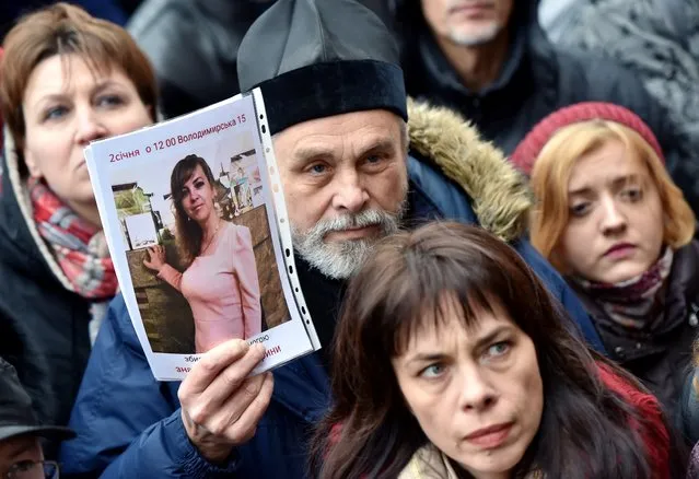 An Orthodox priest holds a picture showing murdered Ukrainian lawyer Iryna Nozdrovska as he together with the other few hundreds activists rally outside the Kiev police headquarters on Junuary 2, 2018. The murder of a Ukrainian lawyer who helped convict her sister's well-connected killer sparked public outrage and a vow by the foreign minister to fight for women's rights. A top Ukrainian human rights group said attorney Iryna Nozdrovska had spent two years trying to keep in jail Dmytro Rossoshansky – the nephew of a Kiev district judge. The case was seen as another test of the much-maligned justice system's ability to fairly prosecute cases of people with connections in the upper echelons of power. (Photo by Sergei Supinsky/AFP Photo)