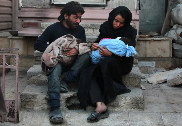 A Syrian man and a woman mourn over the body of one of their children (R) in the rebel- held besieged town of Douma following air strikes on the eastern Ghouta region on the outskirts of the capital Damascus on January 8, 2018. The toddler, named Amir, was wounded during air strikes on the town of Saqba and was evacuated to Douma where he passed away. Regime forces upped the pressure on two of the last rebel bastions in Syria, pounding the Eastern Ghouta enclave near Damascus and the northern province of Idlib. (Photo by Hamza Al- Ajweh/AFP Photo)