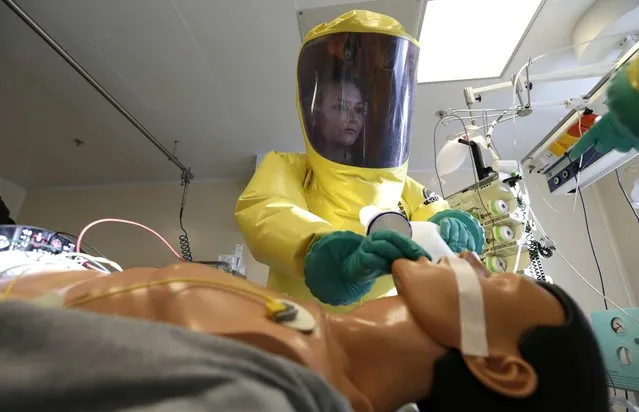 A member of the medical staff of the Biological Defense Center helps conduct a treatment on a dummy during a press demonstration at their facility in the village of Techonin, Czech Republic, Wednesday, November 5, 2014. The Biological Defense Center is capable and equipped for treatment of possible Ebola virus patients. (Photo by Petr David Josek/AP Photo)