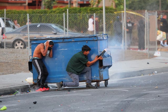 A protester fires a firework during a standoff between police and protesters following multiple detentions by ICE, in the Los Angeles County city of Compton, California, U.S., June 7, 2025. (Photo by Daniel Cole/Reuters)