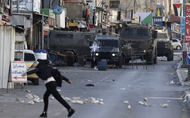 Palestinian protesters hurl rocks at members of the Israeli army during a reported raid in the Palestinian Askar refugee camp near Nablus in the occupied West Bank, on December 18, 2022. (Photo by Jaafar Ashtiyeh/AFP Photo)