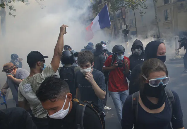 Yellow vest protesters escape tear gas fired by French police while wearing protective face masks as precaution against the conoravirus during a march in Paris, Saturday, September 12, 2020. (Photo by Michel Euler/AP Photo)