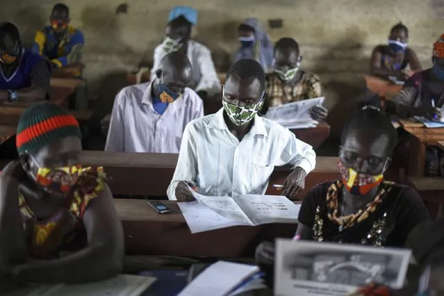 A trainee reads a handbook on coronavirus prevention, at a training session for community health workers conducted by the national NGO “Health Link” in Gumbo, on the outskirts of Juba, South Sudan, Tuesday, August 18, 2020. The coronavirus is exposing an uncomfortable inequality in the billion-dollar system that delivers life-saving aid to countries in crisis: Most money goes to international aid groups instead of local ones and now many local aid workers have been left exposed on the pandemic's front lines. (Photo by Charles Atiki Lomodong/AP Photo)