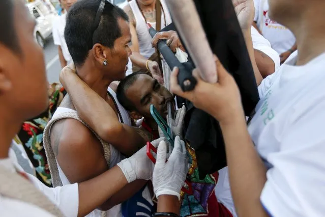 A devotee of the Chinese Ban Tha Rue shrine collapses while having plastic rulers pierced through his cheeks during a procession celebrating the annual vegetarian festival in Phuket, Thailand, October 17, 2015. (Photo by Jorge Silva/Reuters)