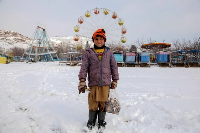An Afghan boy poses for a photograph outside a snow-covered amusement park in Kabul, Afghanistan, 23 January 2023. At least 104 people have been killed in Afghanistan by a powerful cold wave and flash floods in recent weeks, according to the disaster management ministry. Extremely low temperatures, with the minimum dropping to -20 degrees Celsius, and widespread snowfall in large parts of the country including the capital has also resulted in the death of around 70,000 head of cattle. (Photo by EPA/Stringer)