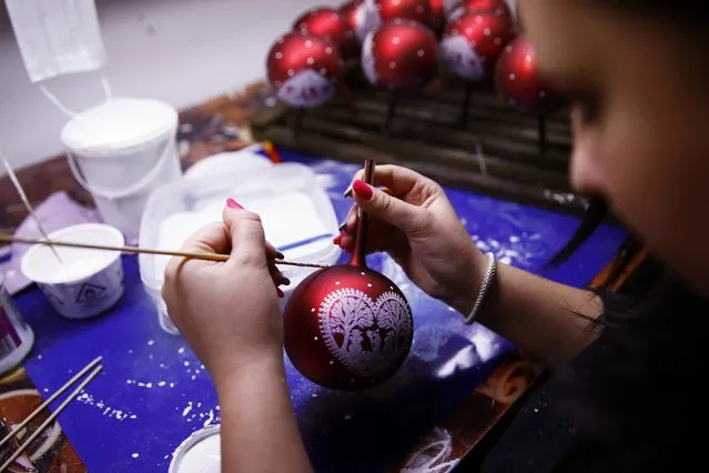 A worker paints Christmas decorations on glass baubles at the Silverado manufacture of hand-blown Christmas ornaments in the town of Jozefow, outside Warsaw December 2, 2014. (Photo by Kacper Pempel/Reuters)